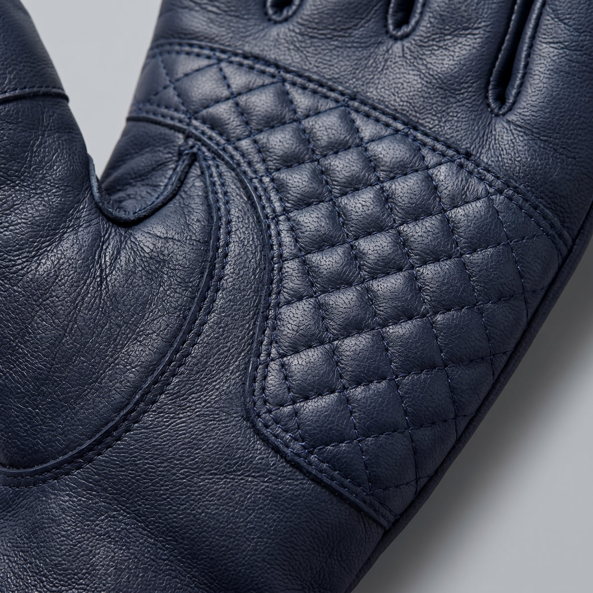 **"Close-up of navy leather glove palm with quilted diamond stitching"**