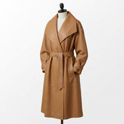 "Angled view of a tan leather trench coat with an oversized shawl collar, tied belt, and flap pockets, displayed on a mannequin against a white background."
