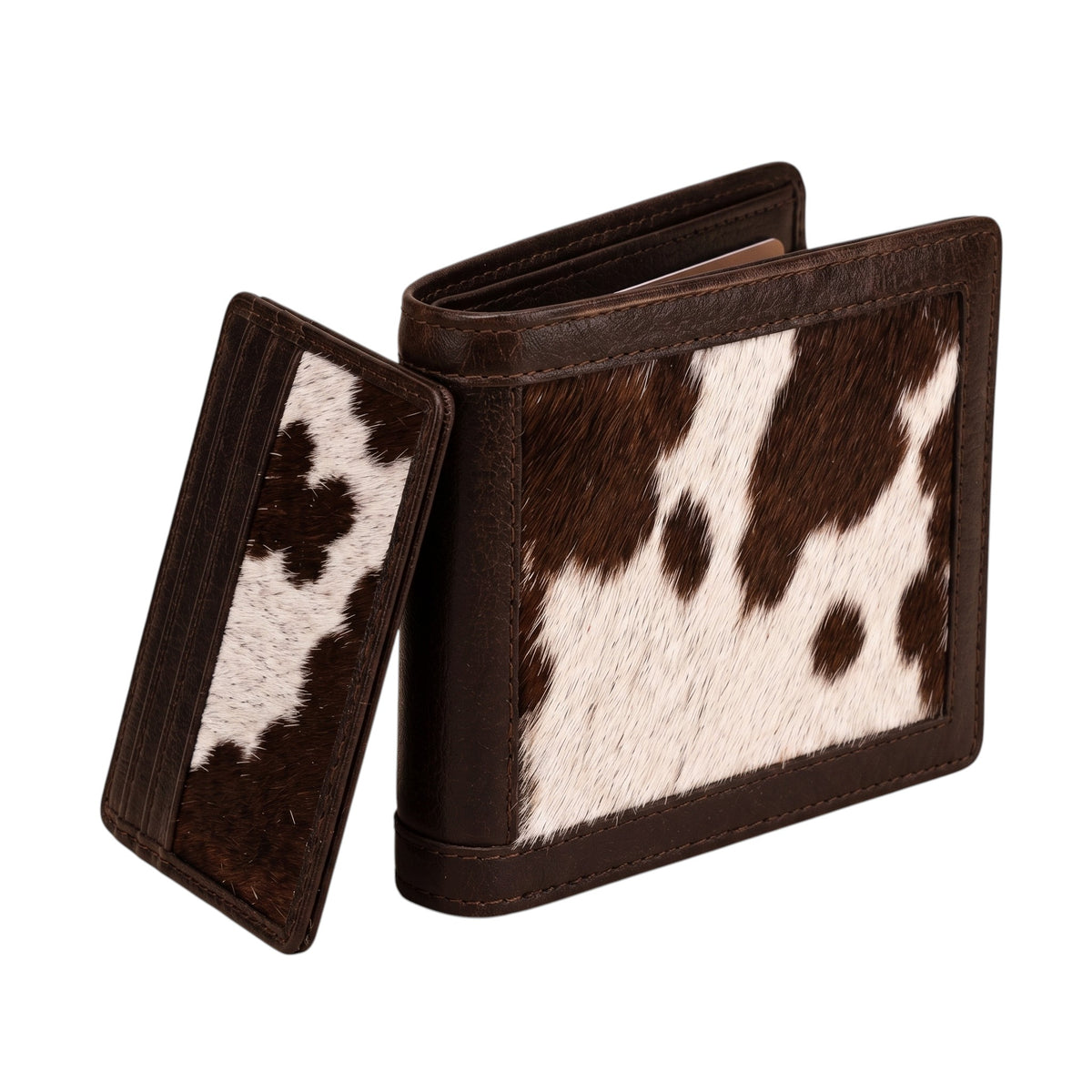 "Two cow-print (brown and white) leather wallets standing upright and leaning together, with dark brown leather trim and stitching, photographed on a white background."