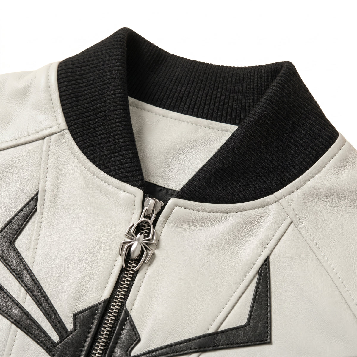 "Close-up of a white leather jacket collar with black ribbed knit trim and a metal spider-shaped zipper pull."