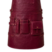 "Close-up of a burgundy leather apron's lower pockets, showing tool slots, a flap pocket, and waist buckles."