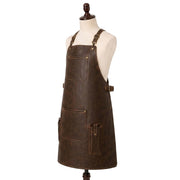 "Three-quarter angle view of distressed brown leather apron on a mannequin, featuring a front chest pocket, dual waist pockets with tool loop, and adjustable neck and side straps."