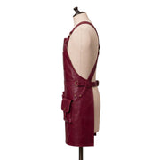 "Side profile view of a burgundy leather apron showing the strap, waist buckle, and a snap-flap pocket." 