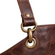"Close-up of brass ring and grommet hardware connecting the strap to the leather apron."