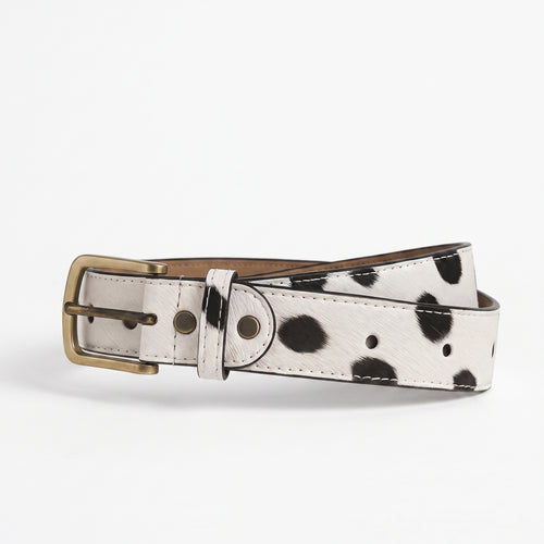 "White leather belt with black spotted (dalmatian/cow-print) pattern, featuring an antique brass buckle and white stitching detail, coiled and photographed on a plain white background."
