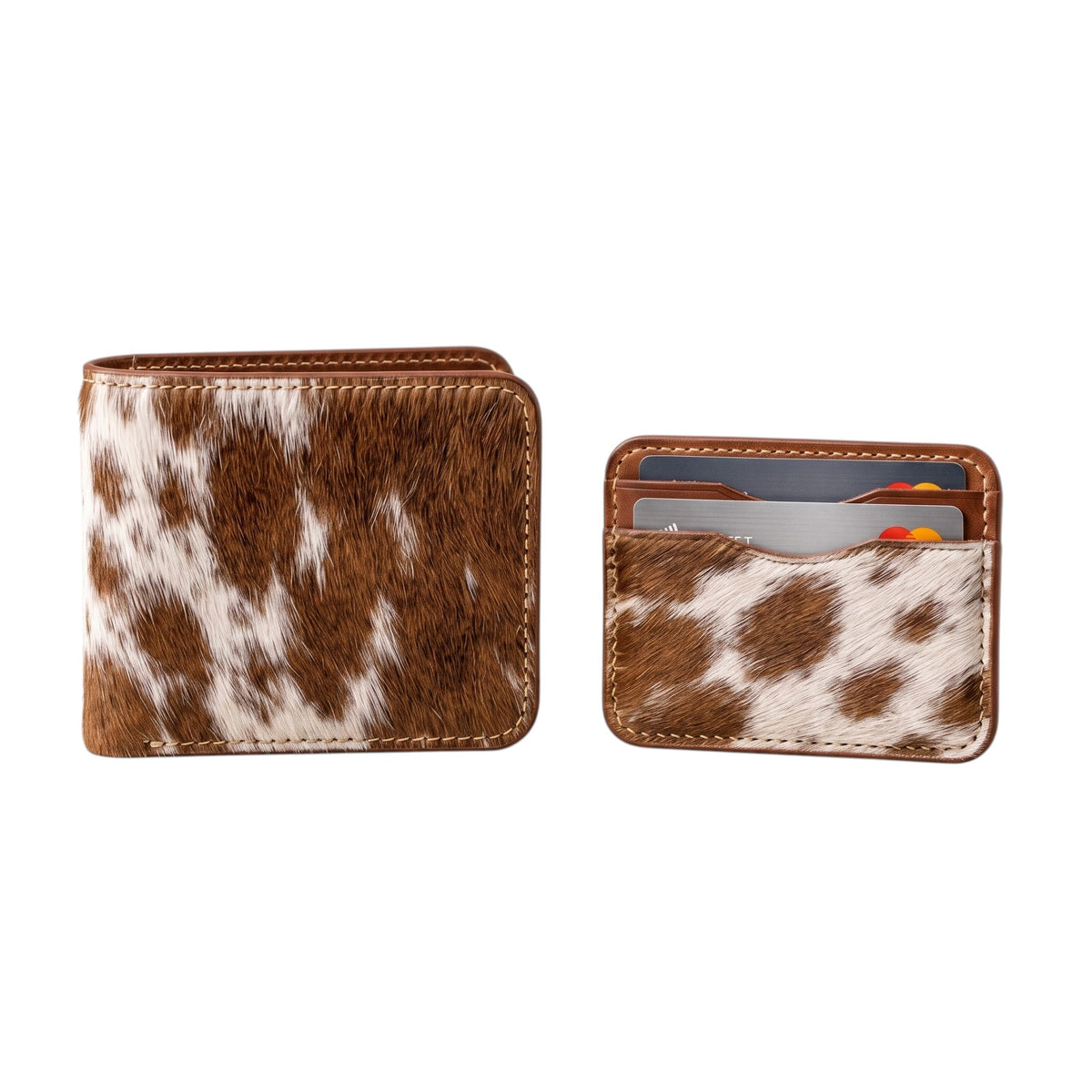 "Closed cow-print (brown and white) leather bifold wallet standing upright on the left, and a matching card holder with credit cards inside standing upright on the right, both photographed on a white background."