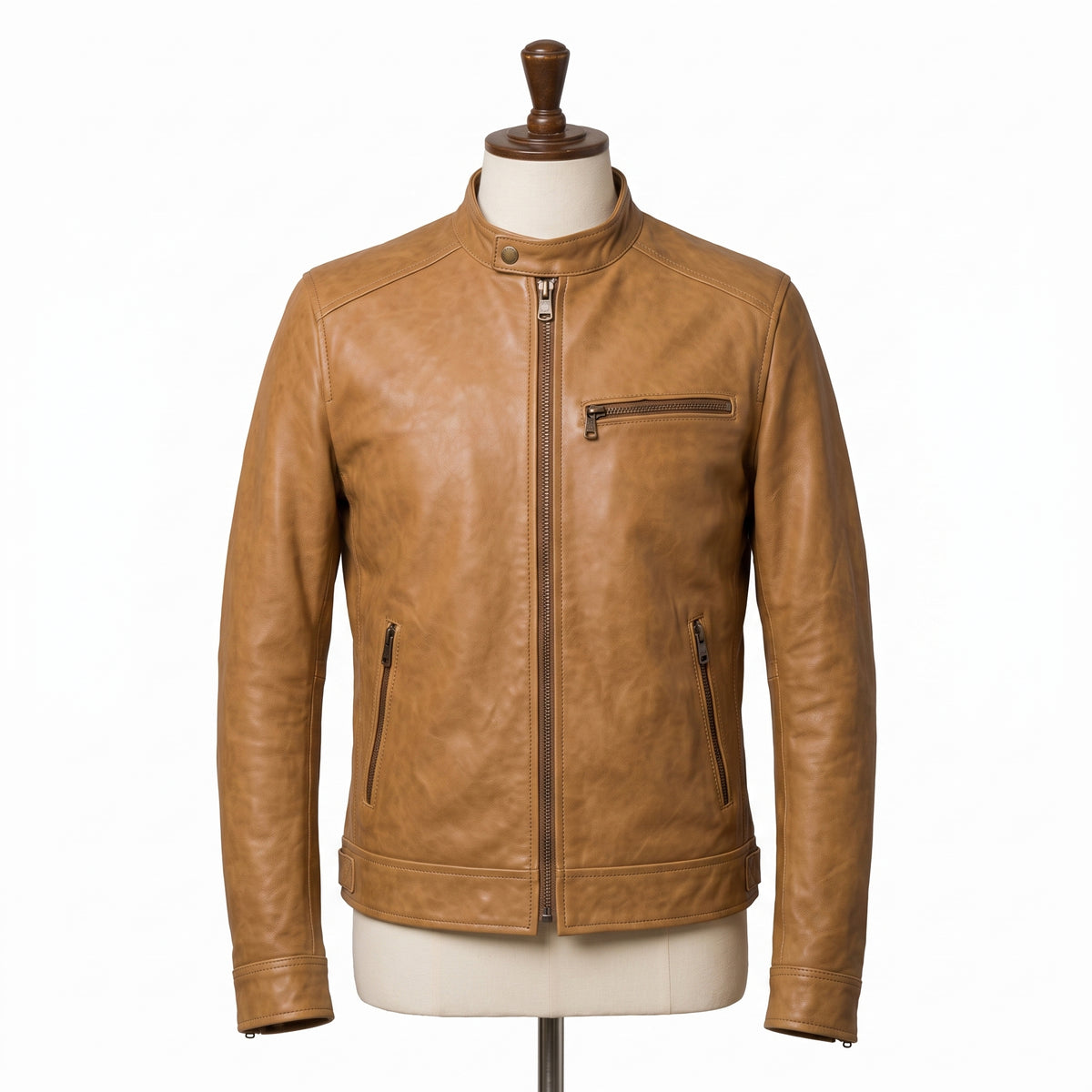 "Full front view of a tan leather biker jacket on a mannequin, showing the band collar, front zipper, chest and side zip pockets, and adjustable waist tabs against a white background."