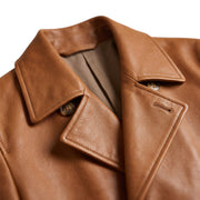 "Close-up of the collar and lapel on a tan leather trench coat, showing a horn-style button, the fabric lining, and leather grain texture."