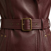 "Close-up of burgundy leather coat's brass buckle belt detail"