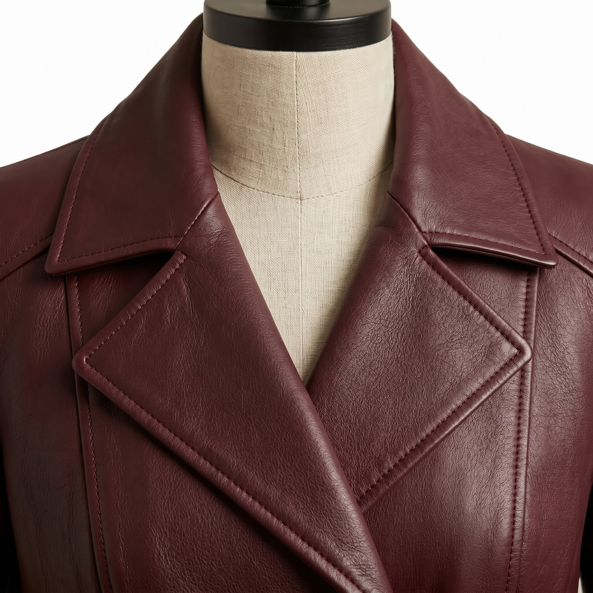 **"Close-up of burgundy leather coat's notched lapel collar and stitching"**