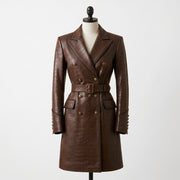 "Front view of a brown crocodile-embossed leather coat with double-breasted gold buttons, notch lapel, belted waist, and flap pockets, displayed on a mannequin against a white background."