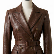 "Close-up of a brown crocodile-embossed leather coat's double-breasted gold buttons, notch lapel, and belted waist."